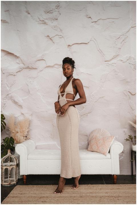 Confident woman in a beige dress posing indoors ne