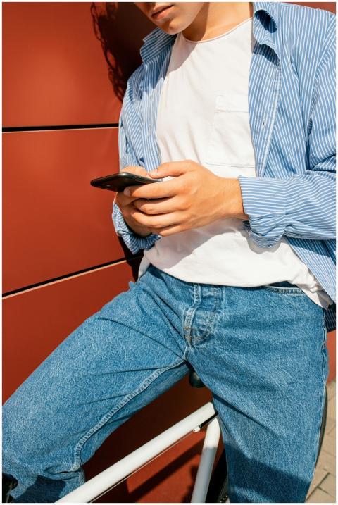 Person in denim pants using a smartphone while sit