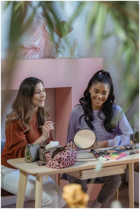 Positive multiethnic female bloggers sitting at ta