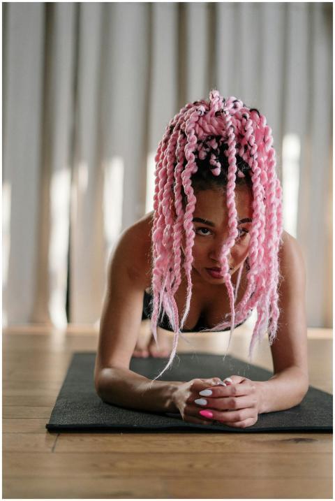 Focused woman with pink hair practicing yoga plank