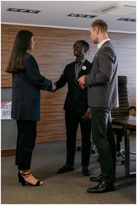 Three professionals in a conference room handshake