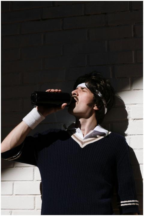 Adult man in sporty attire drinks from tumbler in