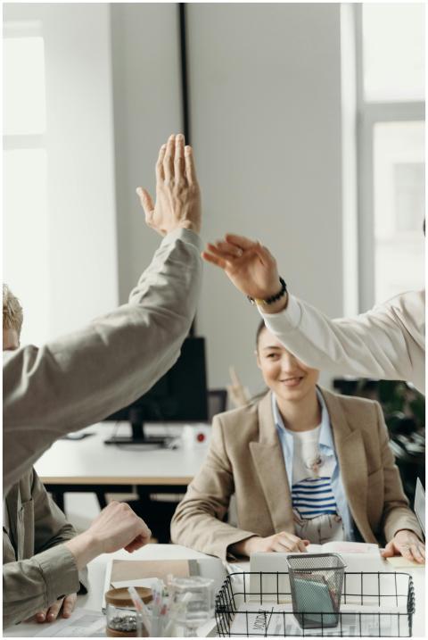 Colleagues in an office exchanging a high five, sy