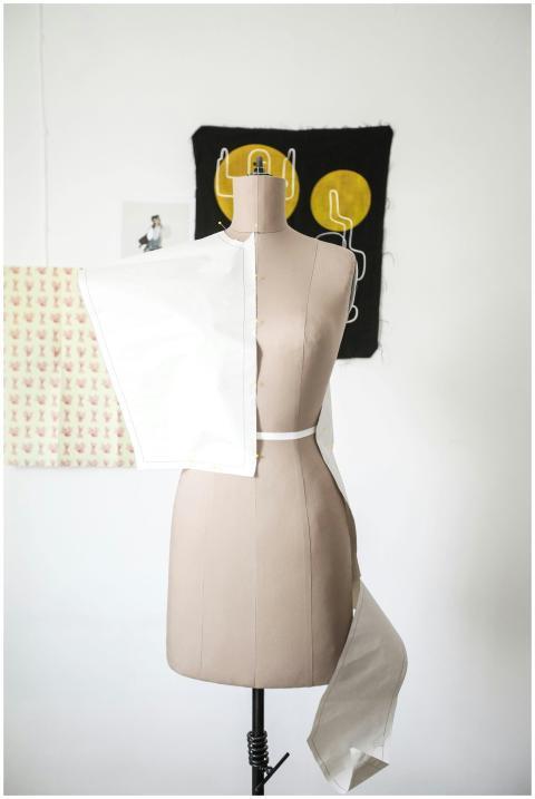 Female mannequin draped with white fabric in a fas