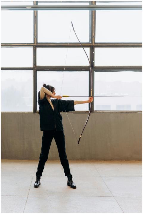 A determined young woman practicing archery indoor
