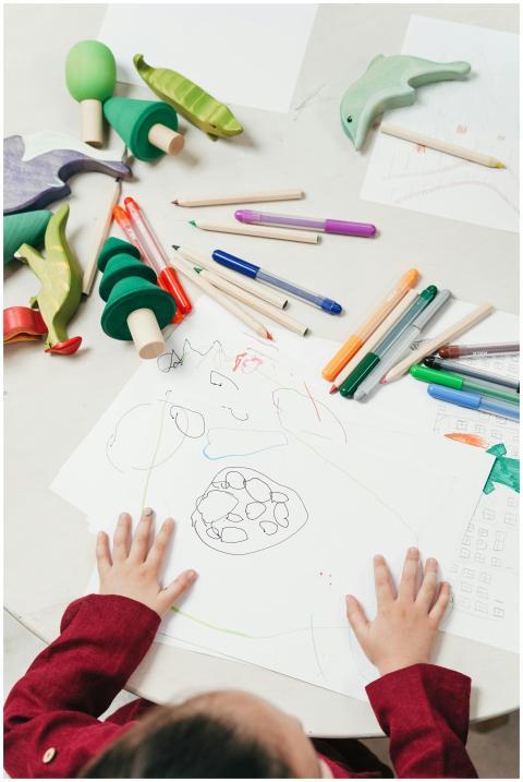 A child engages in creative drawing with colored p