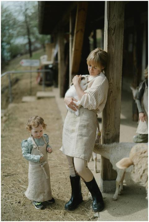 A woman and child in aprons interact with farm ani