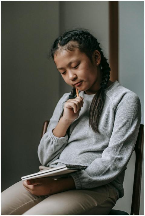 Pensive teenager writing thoughts in a notebook at