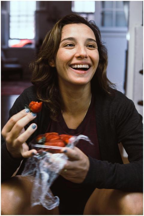 Joyful woman holding strawberries, smiling brightl