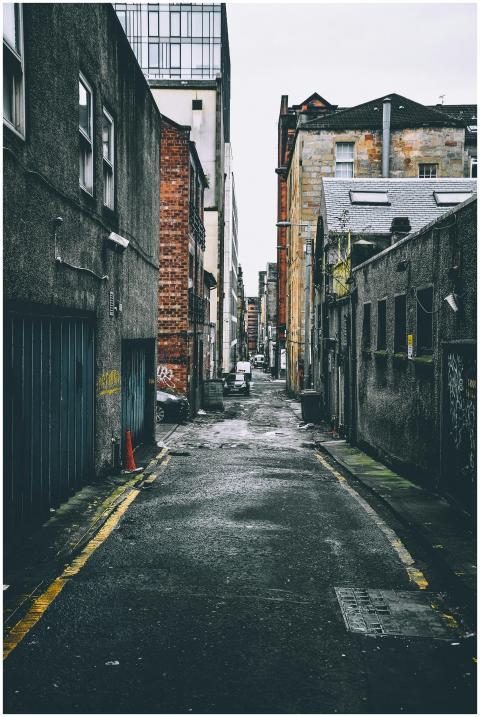 Quiet urban alley with parked cars between old bri