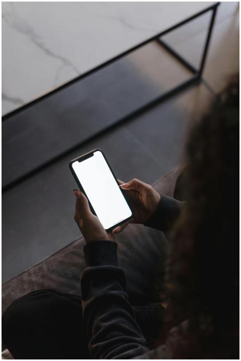 Person holding a blank screen smartphone in a diml