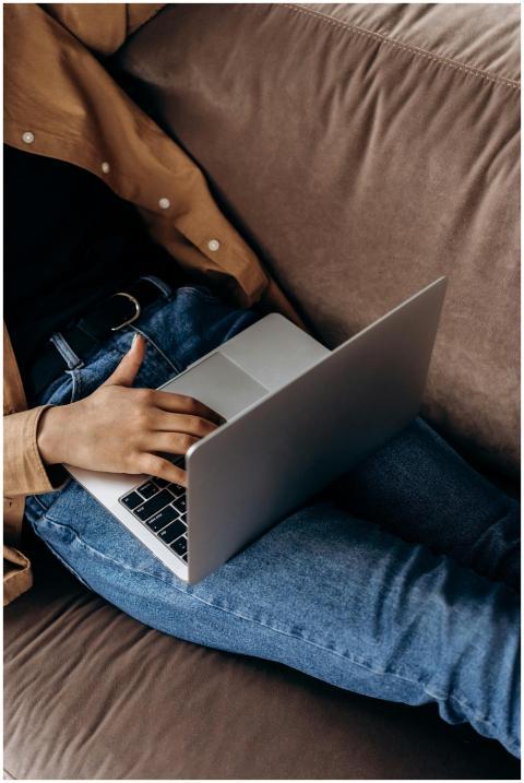 Close-up of a person using a laptop while lounging
