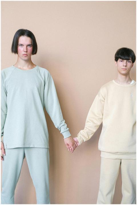 Two people in pastel colors hold hands against a n