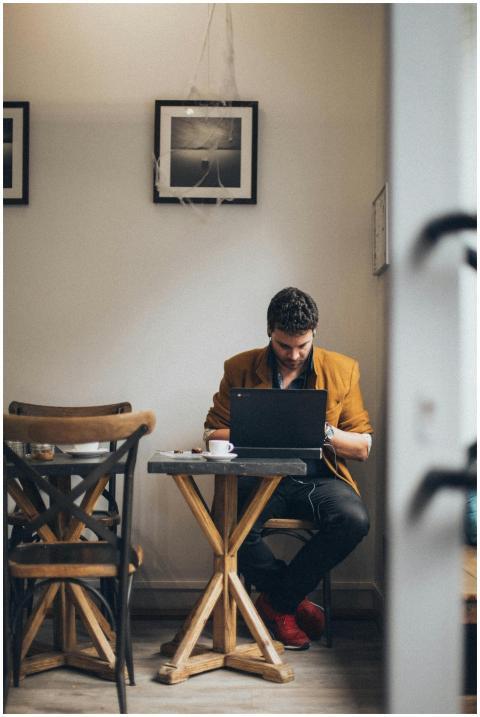A man wearing a jacket is focused on his laptop in