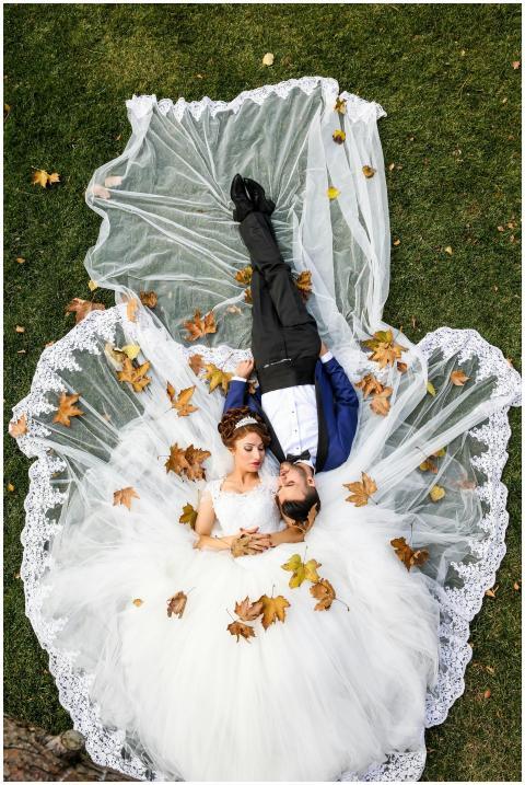 Bride and groom lying together on a lawn surrounde