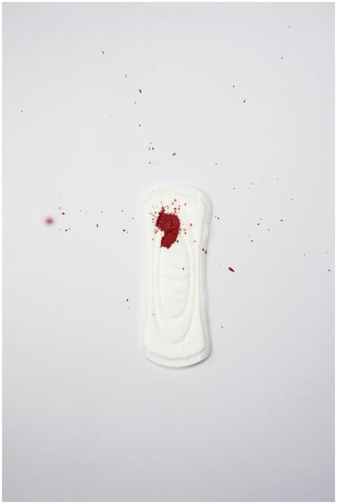 A white sanitary pad with a red bloodstain, highli