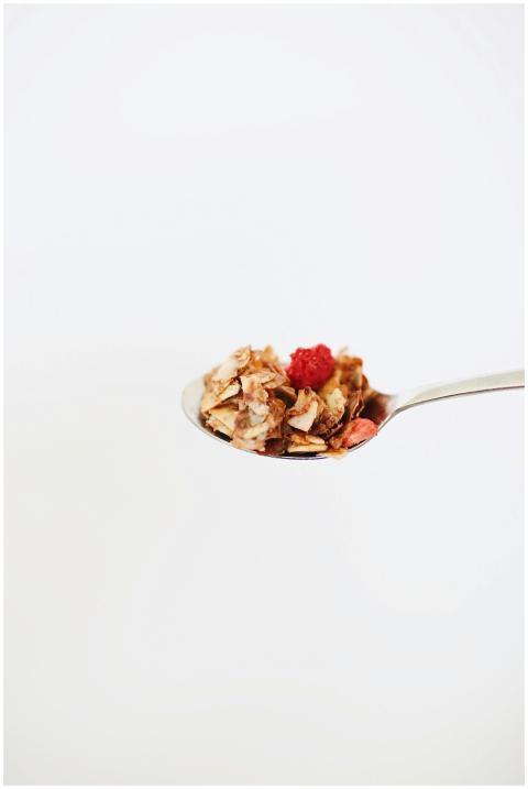 A spoonful of granola topped with a raspberry agai