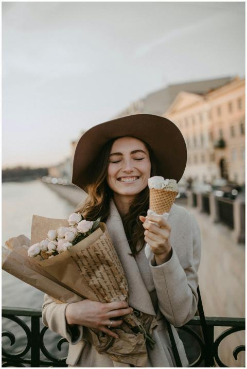 Happy woman with ice cream and flowers by the rive