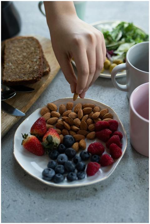 Hand reaching for almonds on a plate with mixed be