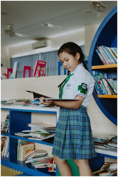 Young girl in school uniform engrossed in reading