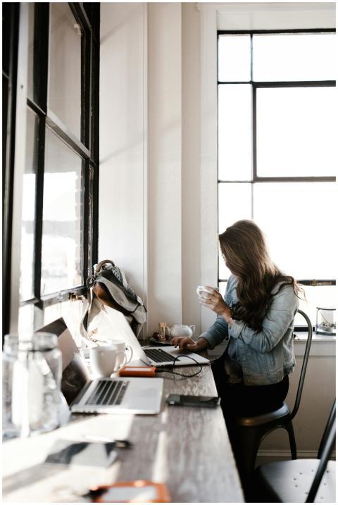 A young woman working on her laptop, sipping coffe