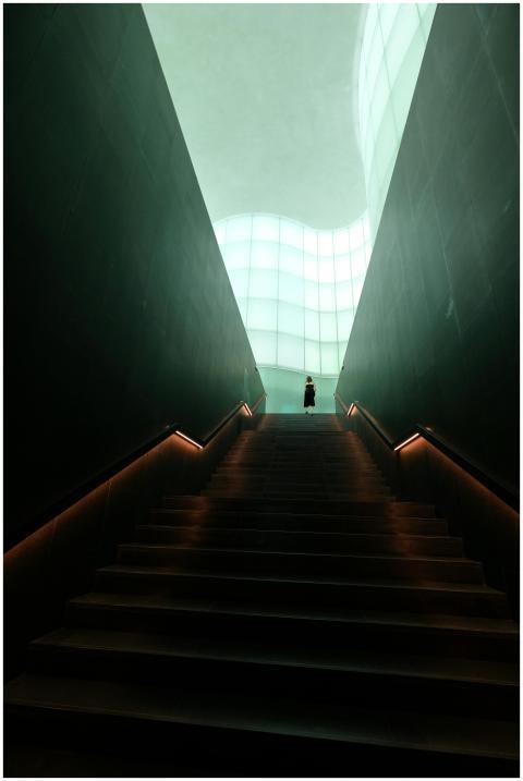 A person stands at the top of a dramatic, well-lit