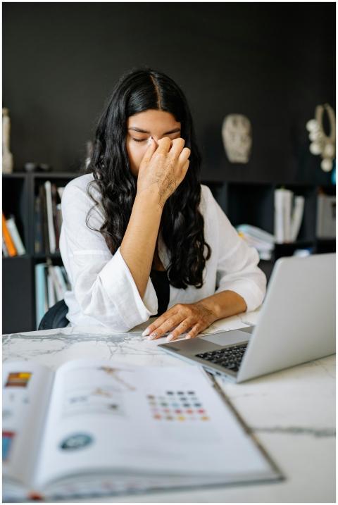 A woman feeling stressed while working on a laptop
