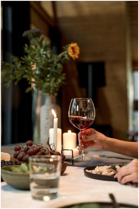 Cozy dining ambiance with a hand holding a red win