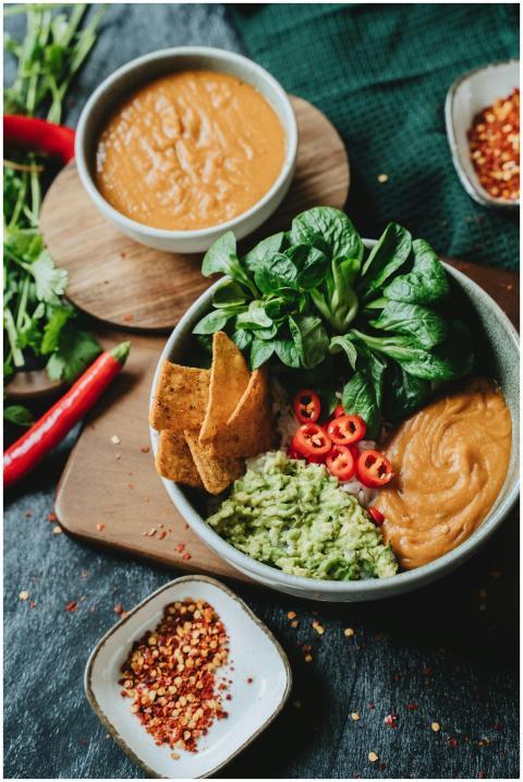 Colorful vegan nacho bowl with avocado sauce, chil