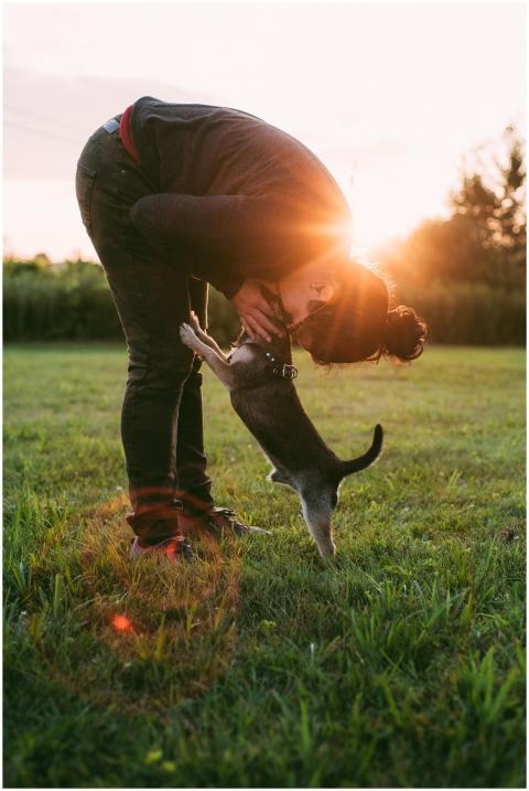 A woman bends down to kiss her playful puppy in a