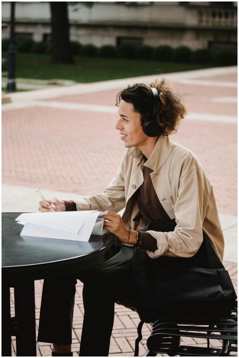 Cheerful student studying outdoors with headphones