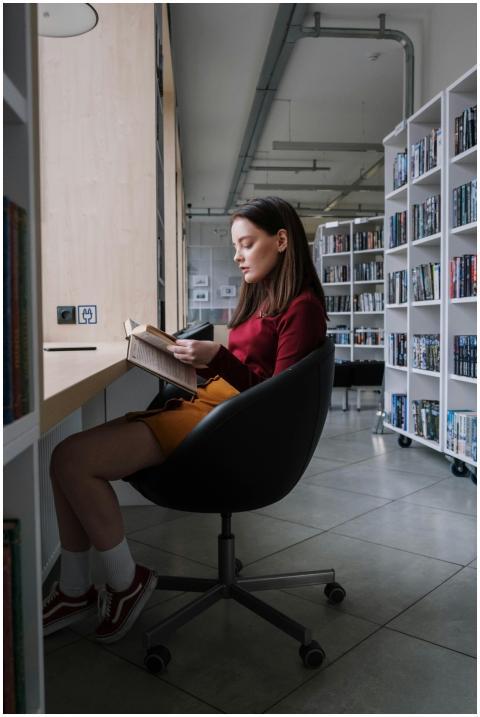 A teenage girl immersed in reading a book while si
