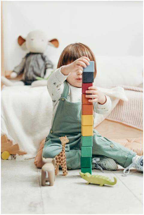 A cute child stacks colorful wooden blocks while p