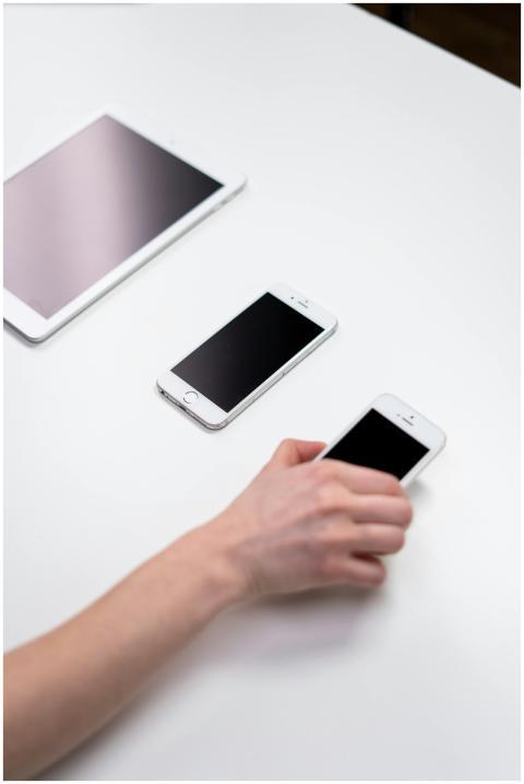 Overhead view of smartphones and a tablet on a whi