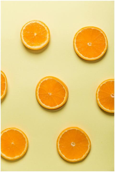 Vibrant sliced oranges arranged on a pastel yellow