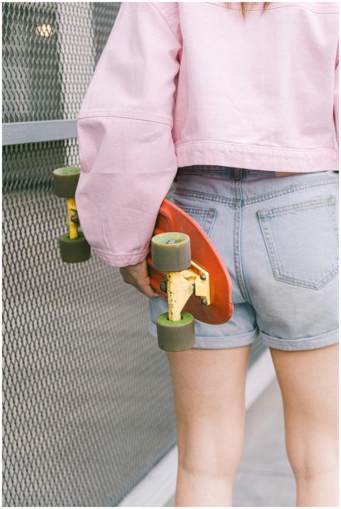 Person holding skateboard in a casual urban scene,