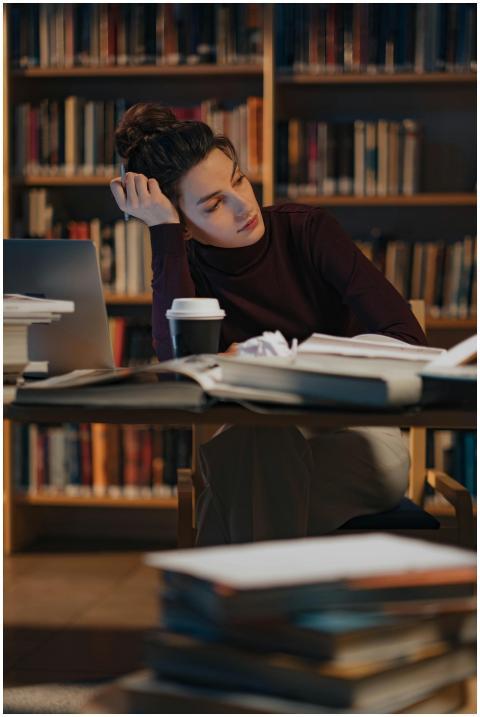 A woman thoughtfully working late in a library fil