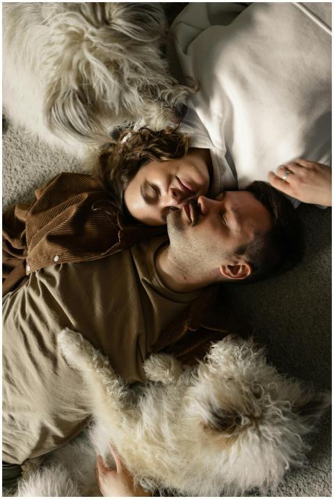 A couple cuddling with their fluffy dogs on a soft