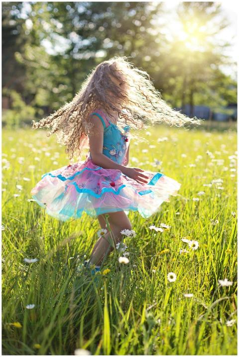 A carefree young girl dancing in a sunlit meadow f