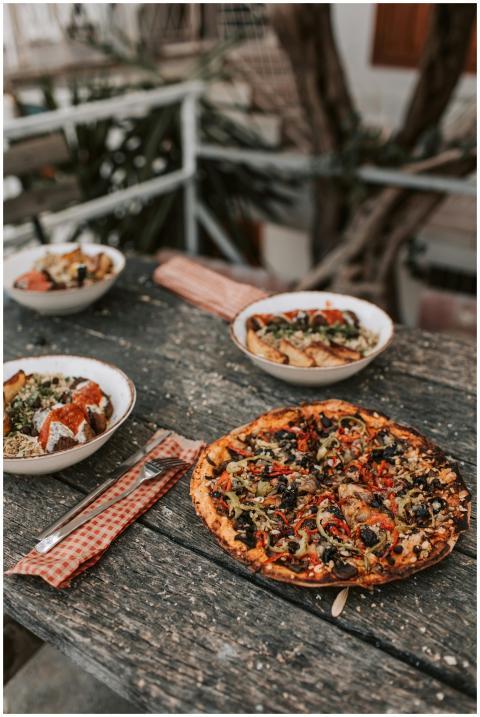 Rustic vegan pizza with healthy bowls on a wooden
