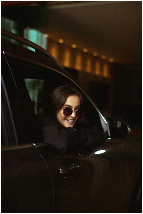 A cheerful woman wearing sunglasses smiles while l