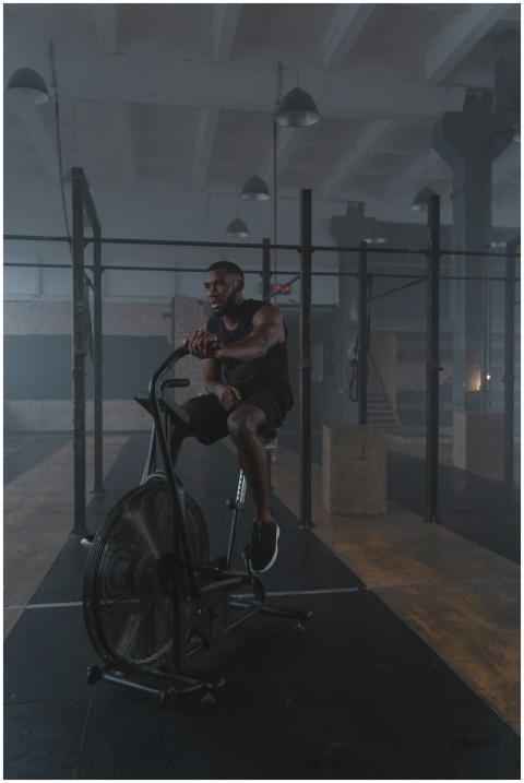 A fit man working out on a stationary bike in a mo
