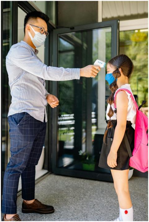 Teacher checks student's temperature at school ent