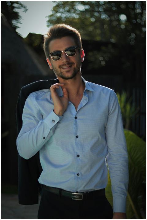 Confident young man in sunglasses poses outdoors i