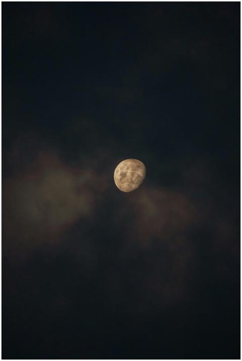 Captured mid-phase moon surrounded by ethereal clo