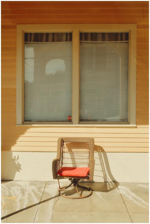 A wicker chair with a red cushion on a sunny New O
