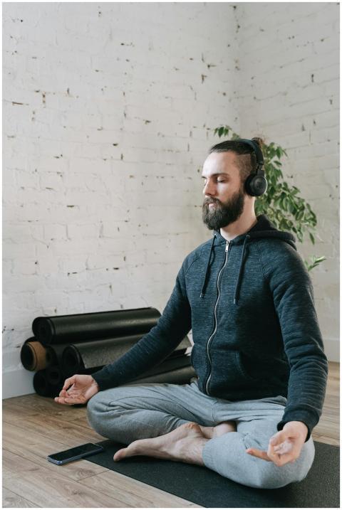 A man meditating indoors with headphones on, promo