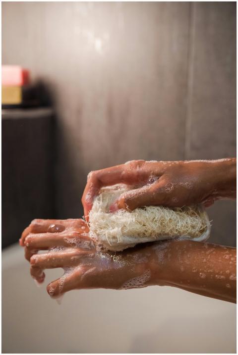 Close-up of hands using loofah and soap for person