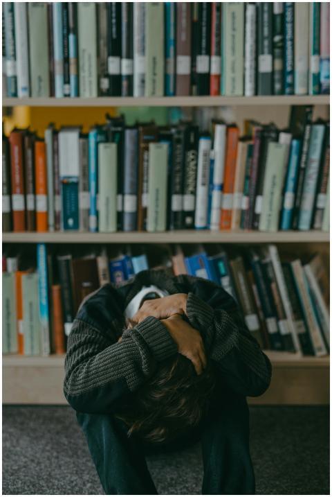 A young boy sitting on the floor in a library, loo
