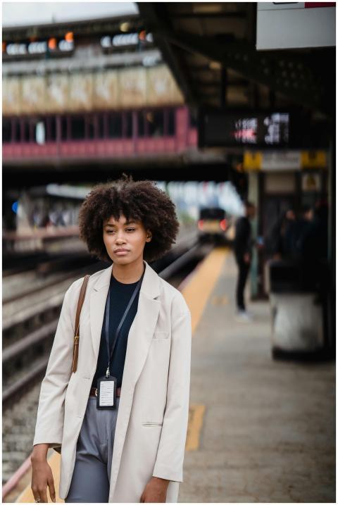 A young woman with curly hair stands at a train st